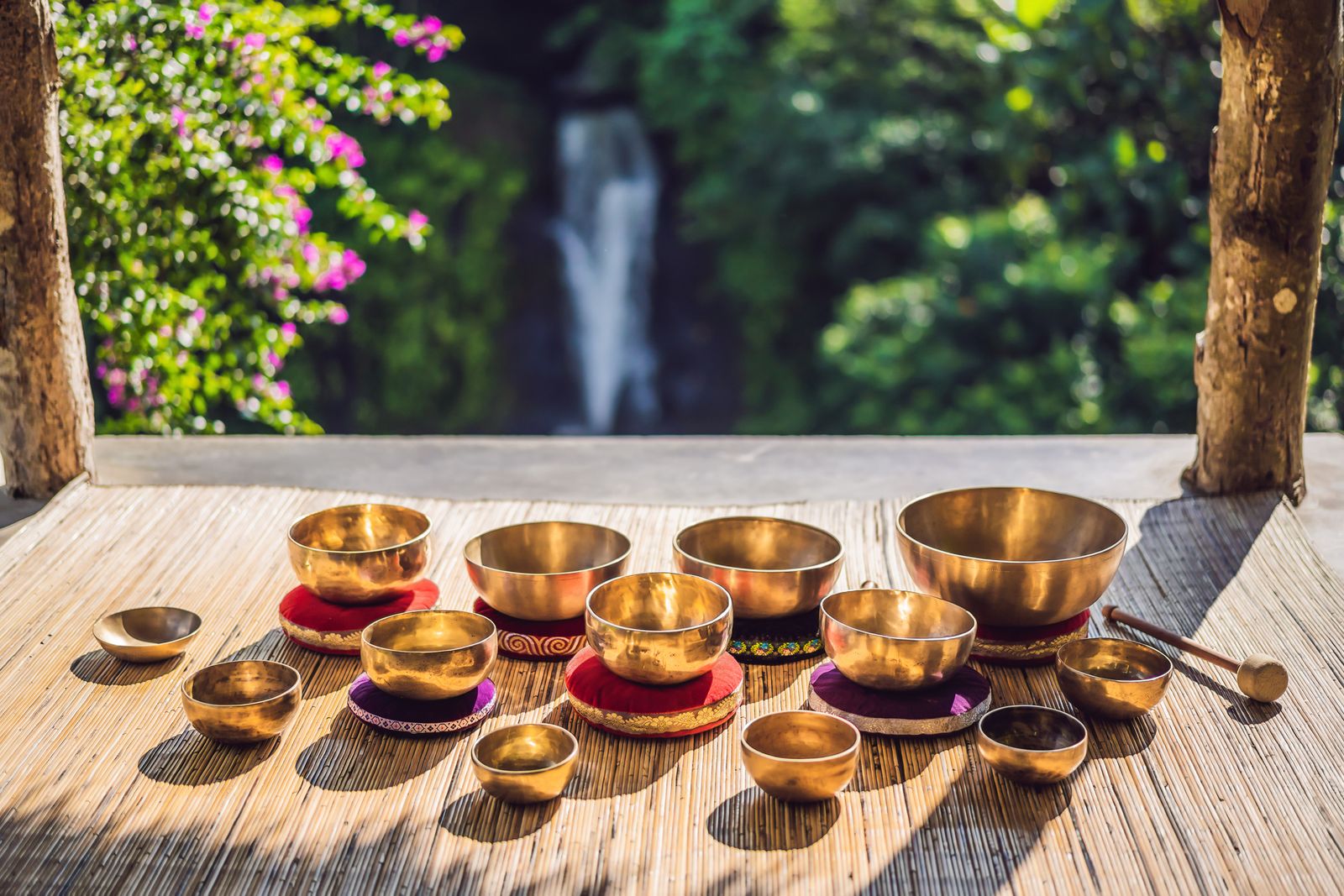 viele Klangschalen auf sonniger Veranda mit Wasserfall im Hintergrund