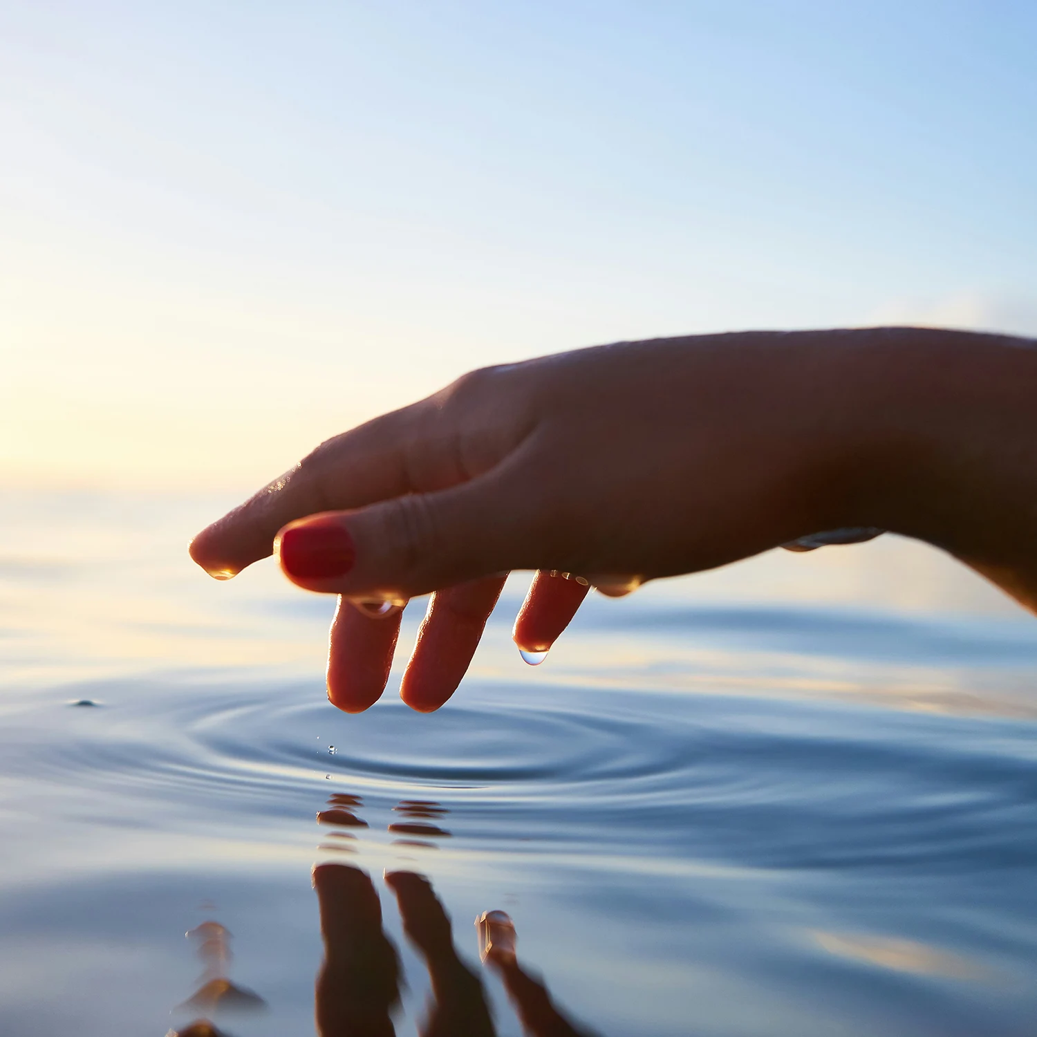 Hand berührt ruhig die Wasseroberfläche